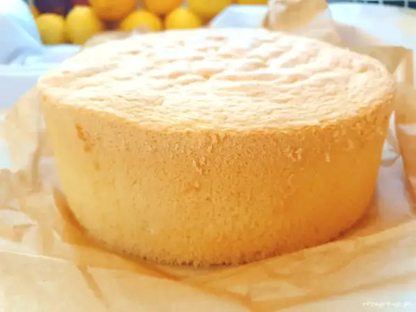 Puszysty, złocisty biszkopt na tort, upieczony na papierze do pieczenia.