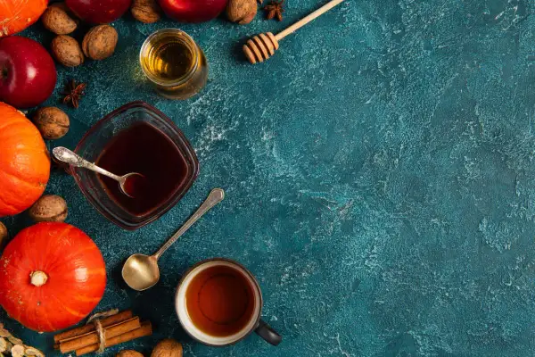 Jesienne składniki: dynie, jabłka, orzechy, cynamon i syrop pumpkin spice w miseczce.